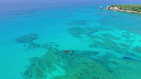 Sunken-Cargo-Shipwreck,-Barco-Hundido,-A-Popular-Diving-Spot-Sits-in-the-Fantastic-Clear-Blue-Waters-of-Las-Galeras-with-Tropical-Backdrop-in-the-Dominican-Republic,-Drone-Aerial