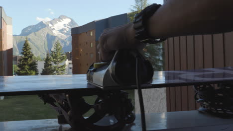 Detail-shot-following-the-iron-while-applying-hot-wax-onto-the-base-of-the-snowboard-in-Les-Deux-Alpes