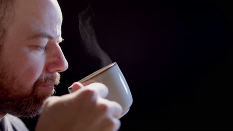 SLOW-MOTION-BACKLIT---A-man-drinks-from-a-steaming-cup-of-hot-beverage