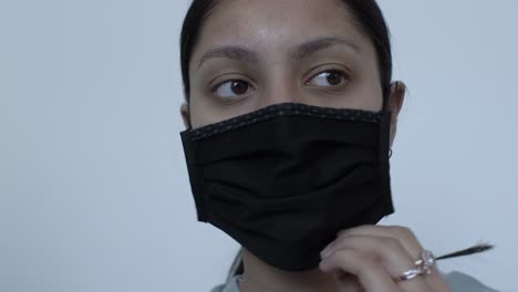 UK-Asian-Female-Teenager-Putting-On-Black-Cotton-Face-Mask