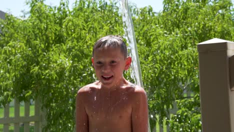 Young-boy-on-a-hot,-summer-day-get-a-bucket-of-water-dumped-on-his-head---slow-motion