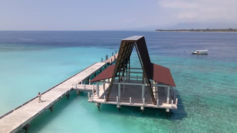 Girl-Walking-Over-A-Wooden-Footbridge-above-crystal-clear-water-of-the-beautiful-indian-ocean-during-sunlight