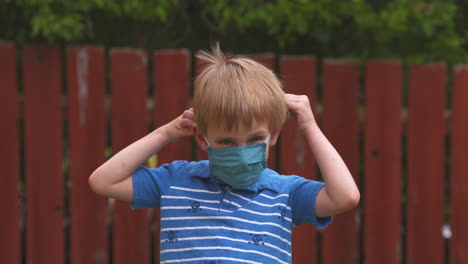 Happy-little-boy-puts-on-a-fabric-mask-to-protect-against-COVID-19-coronavirus