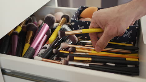 Choosing-Three-Make-Up-Brushes-from-White-Drawer-full-of-Cosmetic-Makeup-and-Beauty-Products