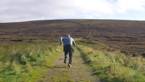 Male-Sprinter-Runs-Fast-On-The-Trail-In-The-Wicklow-Mountains,-Ireland-On-An-Early-Sunny-Morning---long-shot