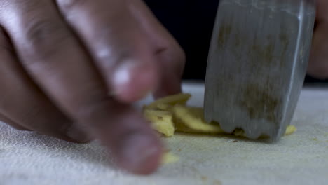 Hand-Of-Ethnic-Minority-Adult-Male-Using-Tenderizer-To-Crush-Fresh-Cut-Ginger-On-Cutting-Board