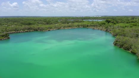 Shot-with-drone-at-low-altitude-over-the-blue-cap-cana-lake,-cloudy-sky,-pleasant-temperature-for-a-dip