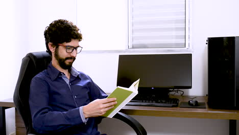 Man-finishes-reading-a-green-book-at-Home-office
