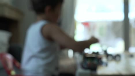 Blurry-shot-of-caucasian-child,-playing-with-toys-on-living-room's-table-120fps,-static-shot