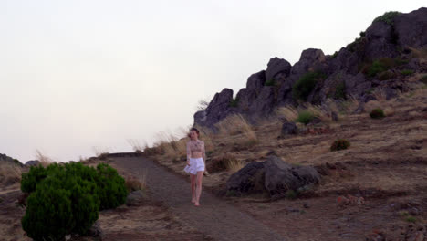 A-young-blond-girl-walks-alone-barefoot-along-a-path-on-top-of-the-mountain-in-the-fog