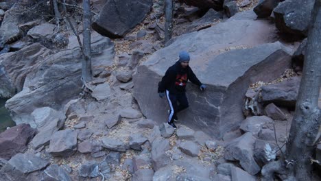 Young-man-hiking-on-red-rocks-in-Zion-National-Park,-Utah