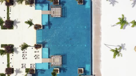 Aerial-top-down-view-directly-above-blue-swimming-pool-of-tropical-resort,-Dominican-Republic