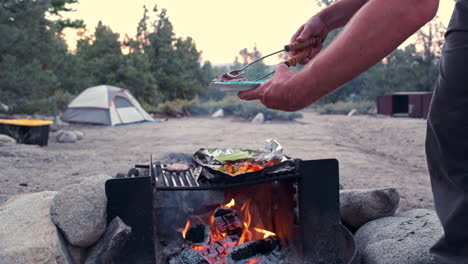 Man-Grilling-Marinated-Steak-and-Vegetables-over-Evening-Campfire