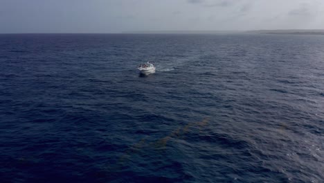 Szenische-Aufnahme-Mit-Drohne-Im-Tiefblauen-Wasser-Des-Offenen-Meeres-In-Cap-Cana,-Mit-Blick-Auf-Das-Weiße-Boot