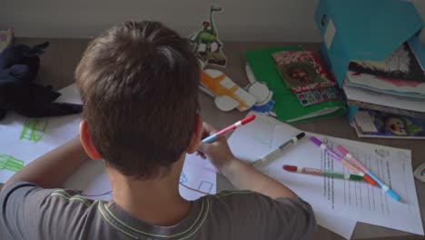 Caucasian-toddler-boy-drawing-with-coloured-markers-at-house-desk