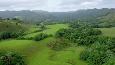 Scenic-flight-at-low-altitude,-beautiful-view-of-the-fields-in-bonao,-green-vegetation,-mountains-in-the-background,-aerial-shot