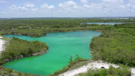 Aerial-shot-with-drone-on-blue-lake,-Cap-Cana-Dominican-Republic-overlooking-the-blue-waters,-clear-sky-golf-cart-passing-by-the-trail