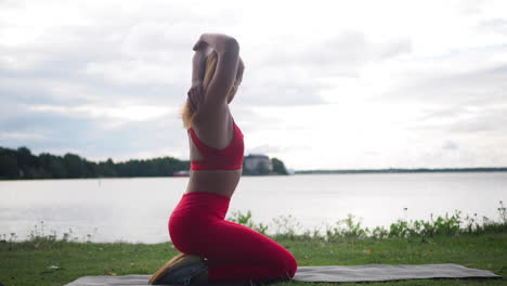 Junge-Frau-In-Roter-Sportbekleidung,-Die-Draußen-Auf-Einer-Yogamatte-Sitzt-Und-Übungen-Macht-Und-Yoga-Praktiziert