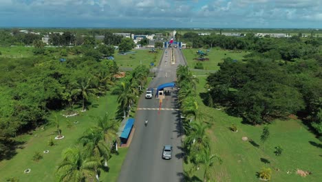 National-Flag-Waves-as-Cars-Passing-Through-the-Security-Checkpoint-Entry-to-Base-Aerea,-Head-Quarters-to-the-Dominican-Republic-Air-Force,-Drone-Aerial