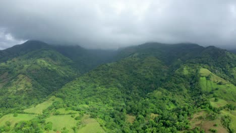Aerial-drone-shot-of-the-green-mountains-in-Bonao,-Dominican-Republic,-gray-clouds