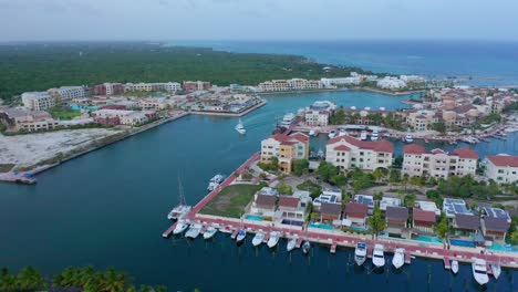Scenic-shot-of-cap-cana-marina,-beautiful-blue-water-buildings,-white-yacht-making-its-entrance