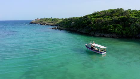 Low-altitude-flight-shaded-by-boat-anchored-in-Diamante-beach,-Cabrera-Dominican-Republic