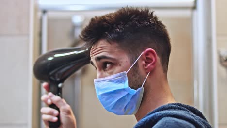 Young-man-with-a-protective-mask-drying-his-hair