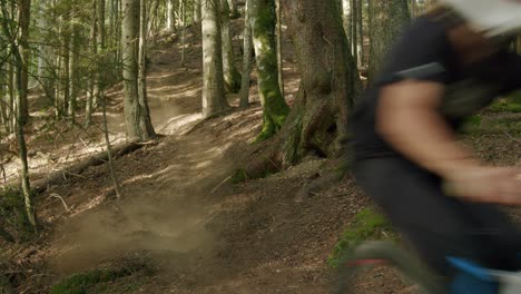 Mountain-biker-rides-down-a-steep-hill-in-a-forest