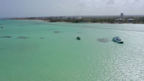 Erstaunliche-Exotische-Tropische-Gewässer-Von-Playa-Juanillio-Beach,-Während-Weiße-Luxusmotorboote-Und-Yachten-Vor-Anker-Sitzen,-Dominikanische-Republik,-Drohnenantenne