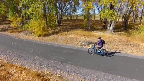 Senior-man-cycling-along-a-nature-trail-in-Autumn---aerial-view