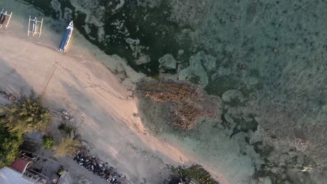 Frau-Blickt-In-Die-Drohnenkamera,-Die-Auf-Felsen-Steht,-Die-Von-Klarem-Meerwasser-Der-Insel-Gili-Air-Umgeben-Sind