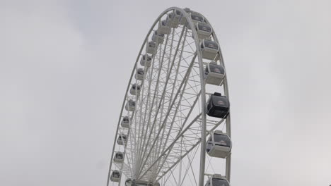 Large-ferris-wheel-slowly-turning-against-gray-overcast-sky