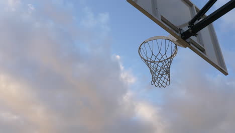 Aktionsaufnahme-Des-Basketballs,-Der-Durch-Einen-Basketballkorb-Und-Ein-Netz-Gegen-Den-Blauen-Himmel-Geht