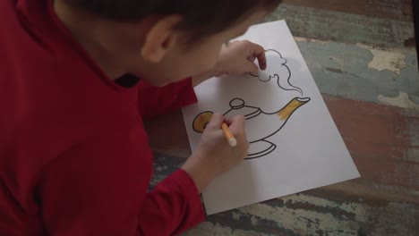 Caucasian-boy-painting-a-magic-lamp-draw-using-a-yellow-marker-indoors