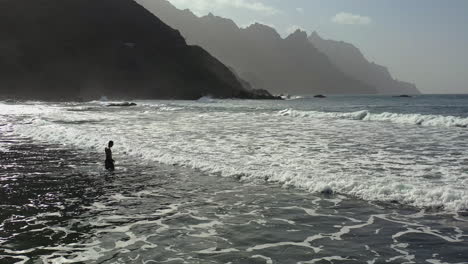 Mann-Zu-Fuß-Gegen-Meereswellen,-Berge-Dahinter,-Teneriffa,-Kanarische-Inseln,-Spanien