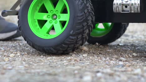 Close-up-shot-on-parts-of-RC-monster-truck-toy,-moving-on-soil-ground-120fps