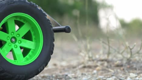 Close-up-on-front-wheels-of-Rc-monster-truck,-moving-back-and-forth-on-soil-ground-120fps