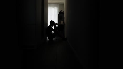 Silhouette-of-Sad-Desperate-Man-in-house-hall-way-Sitting-On-Ground