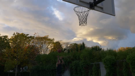 Man-Practicing-A-Two-Point-Shot-Playing-Alone-At-The-Basketball-Court-During-Sunset-In-Vancouver,-Canada---Medium-Shot