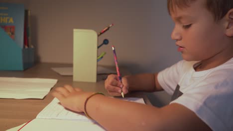 Footage-of-caucasian-six-years-old-boy,-doing-his-homework-lessons-at-home-4K,-side-view,-medium-static-shot