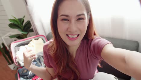 Lovely-blogger-recording-video-selfie-while-packing-a-suitcase-for-a-travel-trip