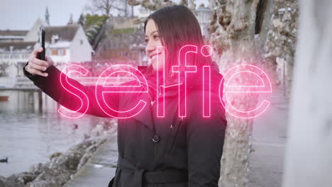 Young-female-model-taking-selfies-on-vacation-in-small-wintry-town-on-the-bank-of-a-river