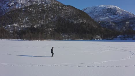 Aerial-fast-orbiting-around-man-ice-skating-on-idyllic-scenery-on-Norwegian-mountains
