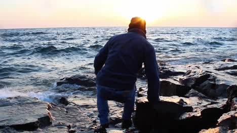 Guy-standing-next-to-lake-superior-shore-on-a-sunrise,-freedom-travel