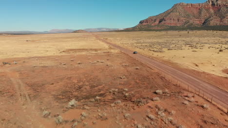 Slow-Push-in-on-Station-Wagon-with-Bike-Rack-on-Desert-Road,-Aerial