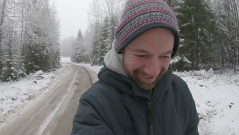 An-ecstatically-happy-man-in-his-30s-walks-along-a-snowy-road-in-the-countryside