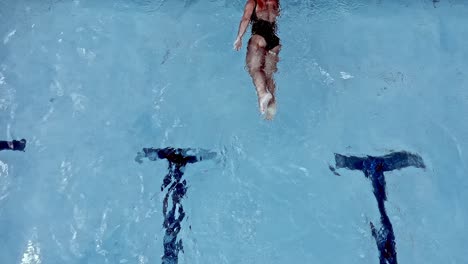 A-woman-swimming-in-a-pool-reaches-the-end-of-the-lane-and-turns-to-complete-another-lap---overhead-slow-motion