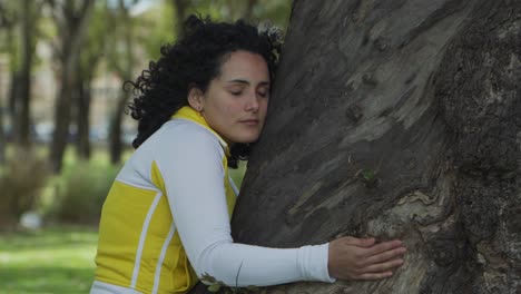 Nahaufnahme-Einer-Jungen-Attraktiven-Brünetten-Aktivistin,-Die-Mit-Geschlossenen-Augen-In-Einem-Park-Einen-Baum-Umarmt