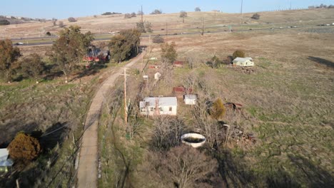 Drone-real-time-footage-over-Clarksville,-California,-USA,-along-the-main-road-showing-traditional-houses,-trees-and-rural-farmland,-moving-forward-towards-the-highway-and-passing-traffic