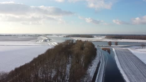 Flying-towards-a-river-above-a-frozen-ditch-in-a-winter-landscape